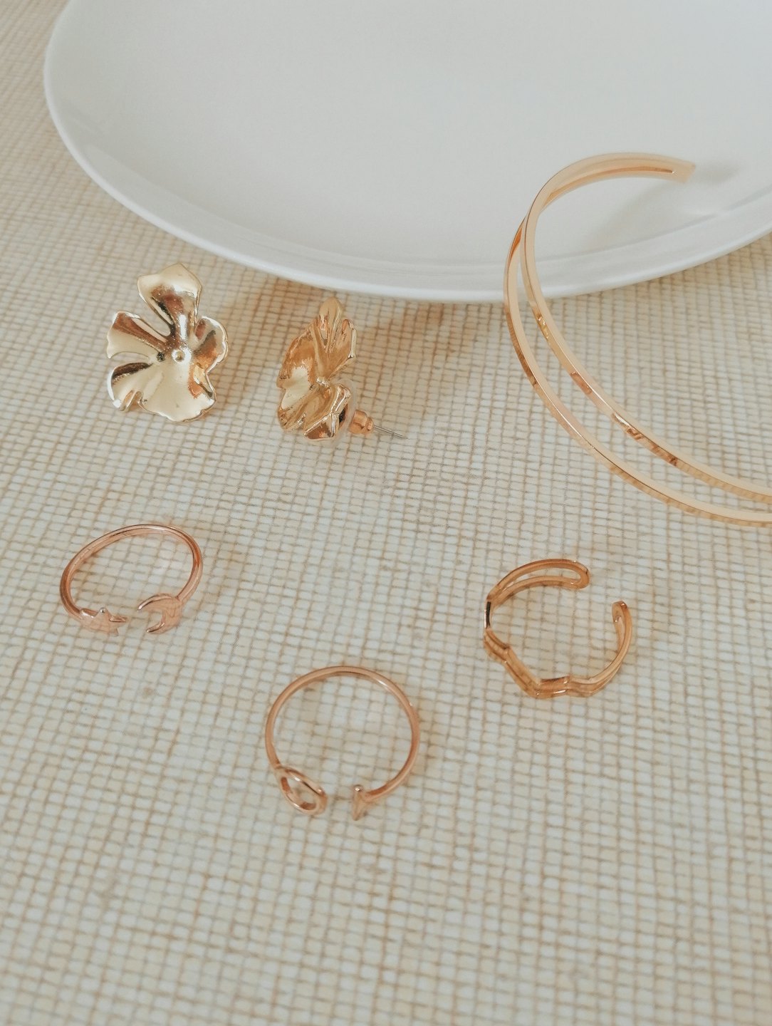 Delicate gold jewelry laid out on a textured beige cloth.