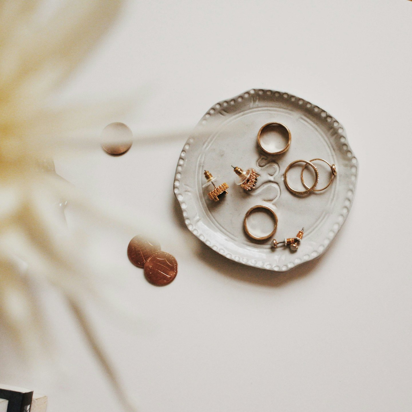 Gold jewelry and coins arranged on a decorative plate.