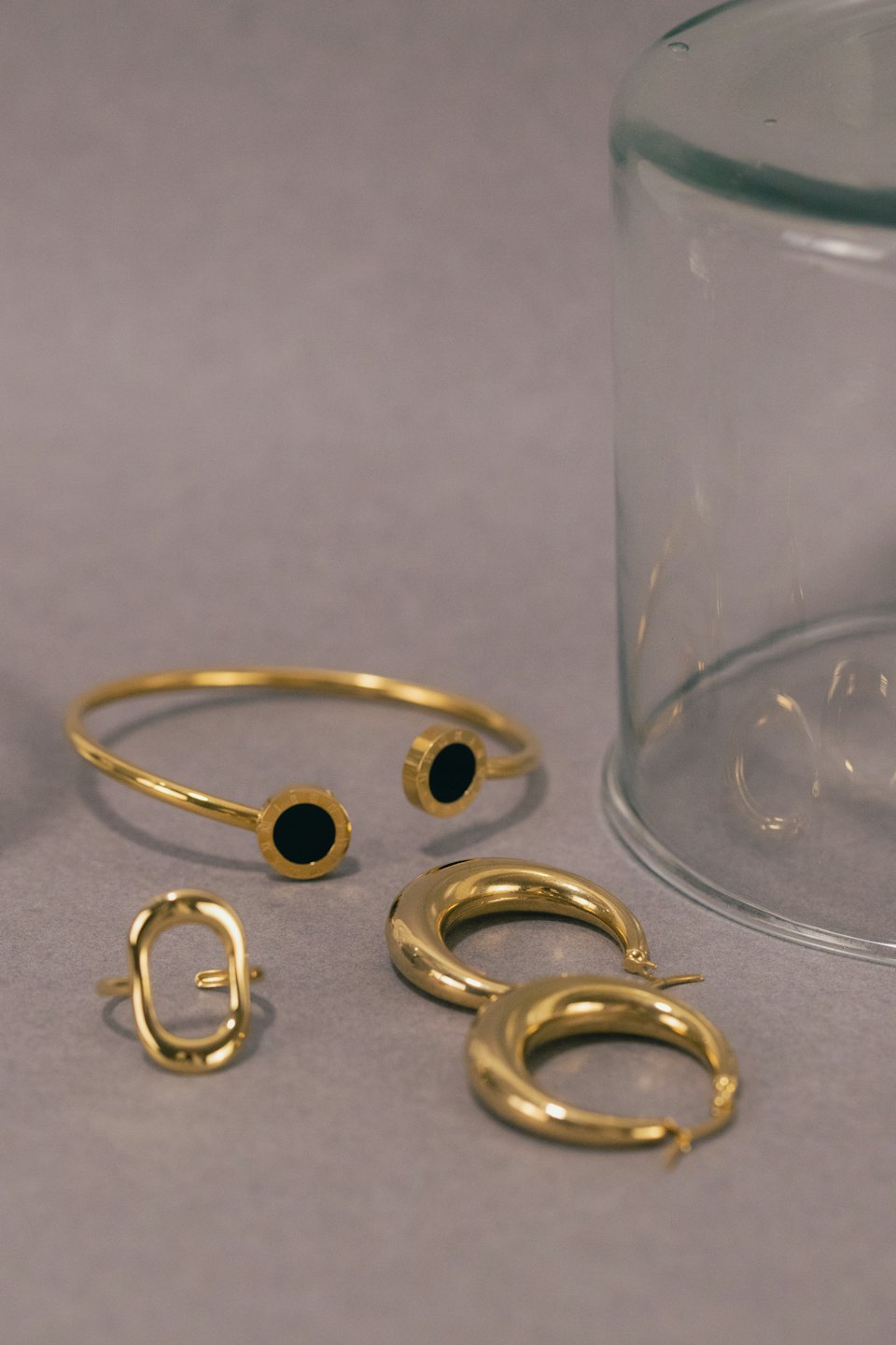 Gold jewelry set displayed on a smooth grey surface.