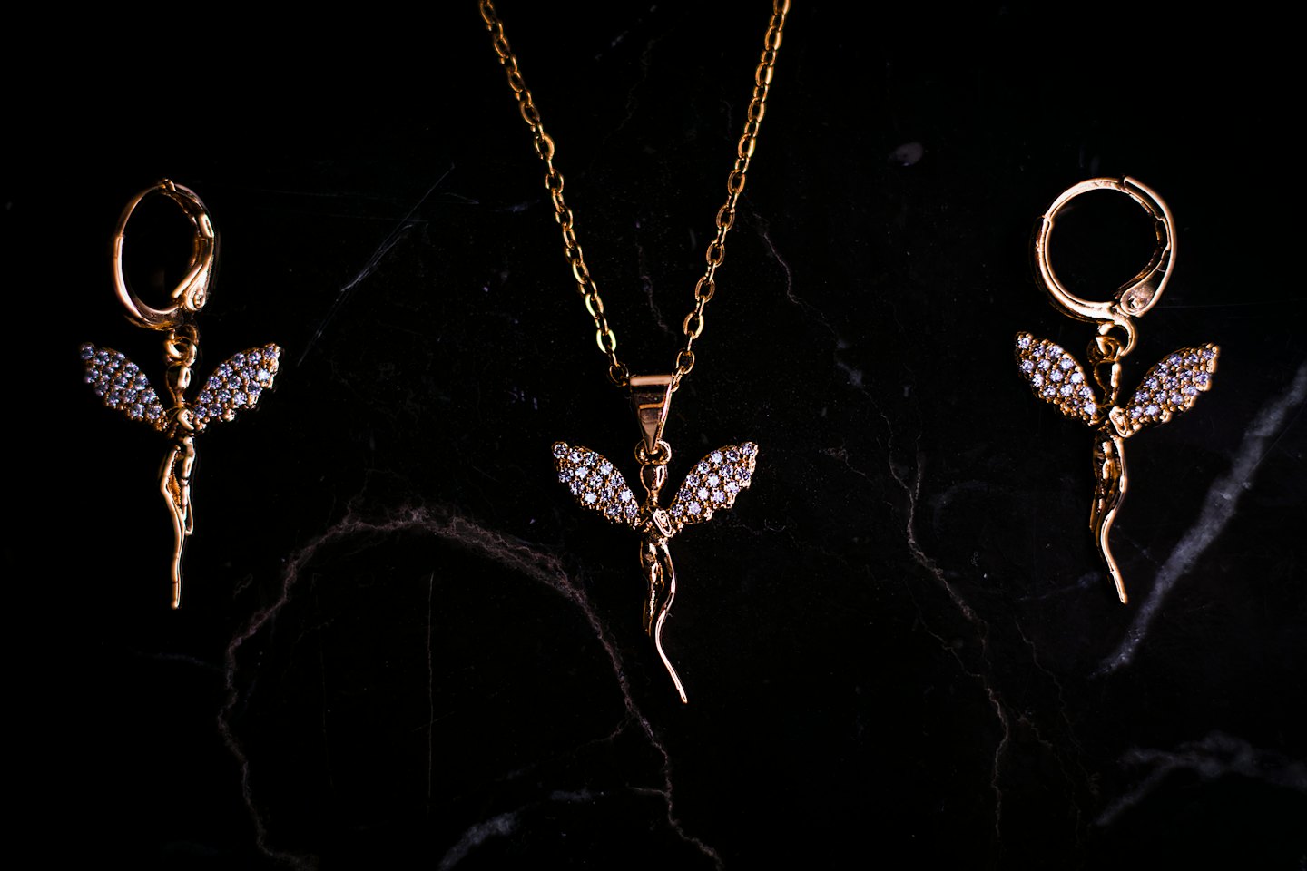 Gold crystal jewelry set arranged on black marble.