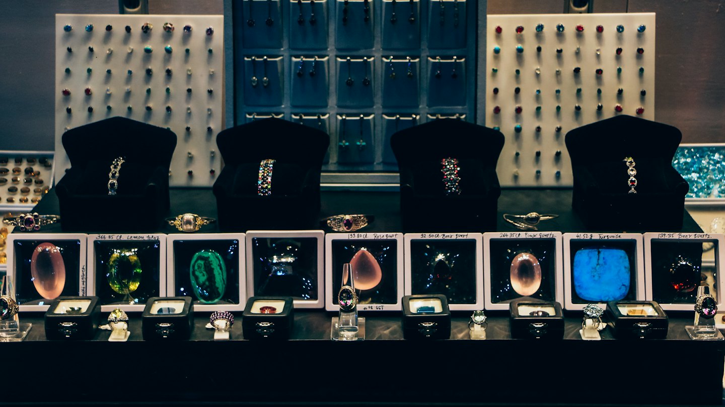 Gemstones and jewelry displayed on stands inside a retail case.