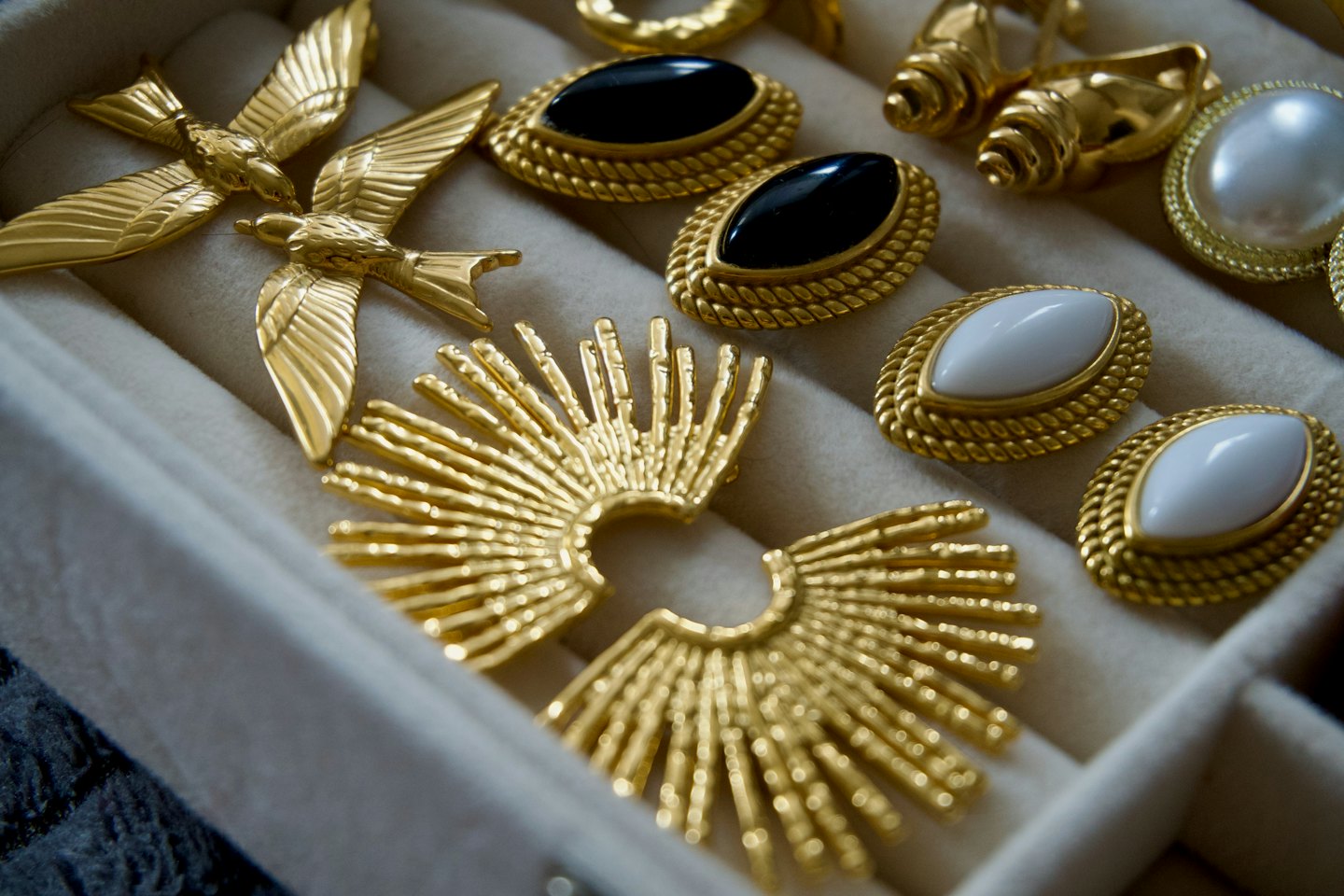 Gold jewelry and brooches arranged inside a velvet jewelry box.